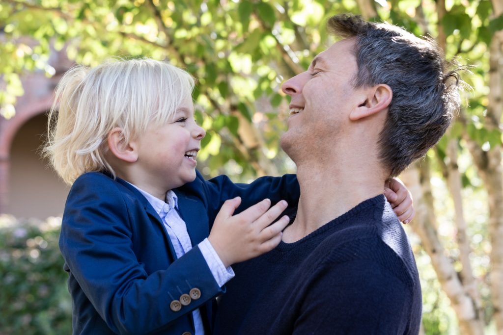 outdoor family photography of a father holding his son and looking at each other whilst laughing
