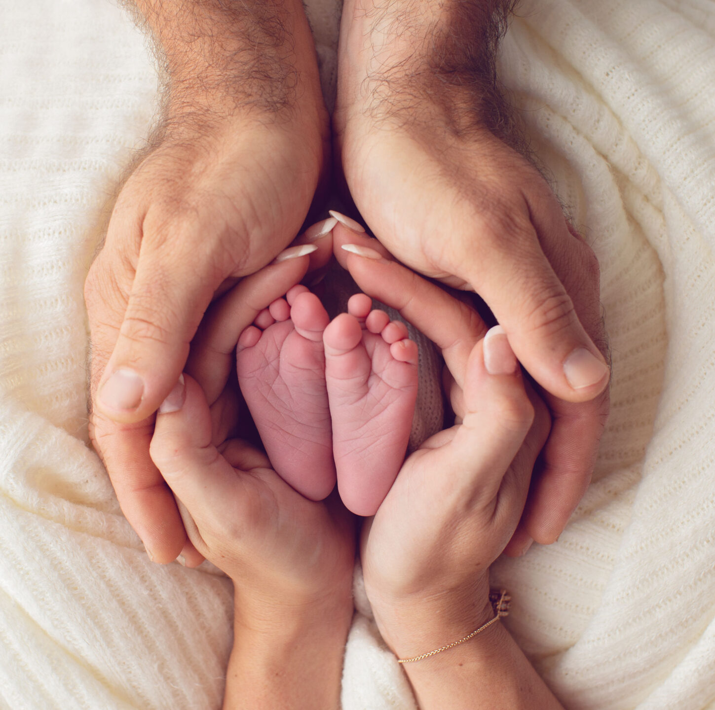 Newborn baby's feet held in parent's hands taken by Birmingham newborn photographer at The Custard Factory