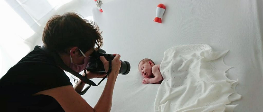 Birmingham newborn photographer Daniella Staub taking a photo of a baby on a white blanket.