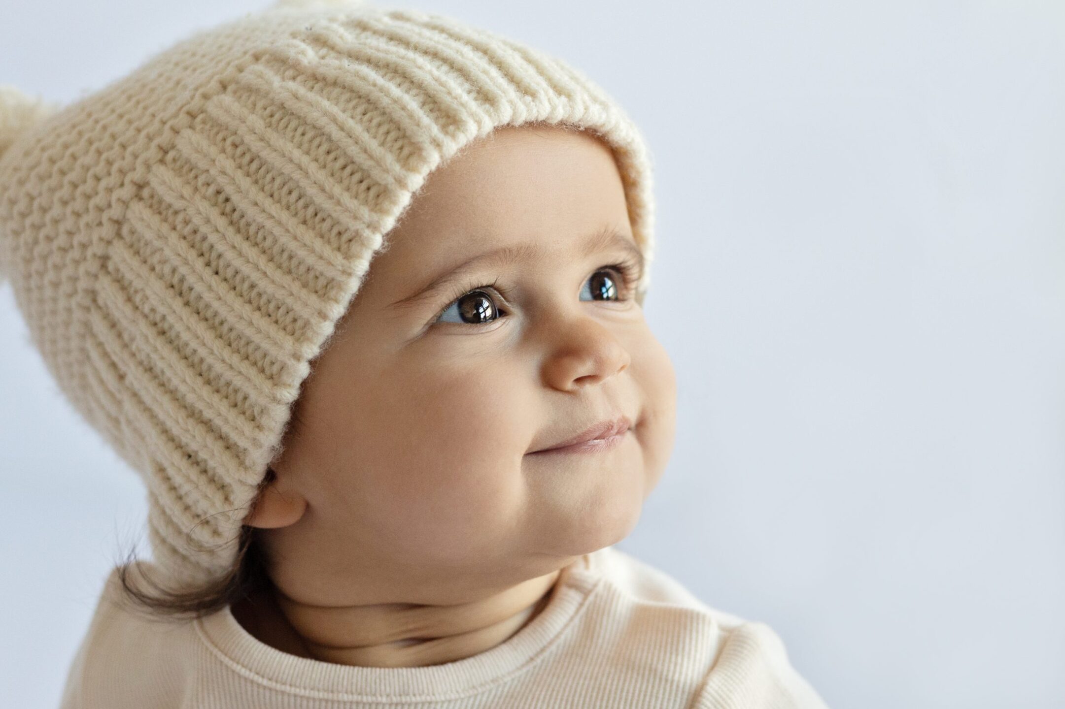 Close up of brown eyed child with a white wollen hat