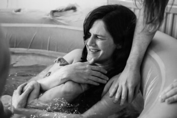 black and white photo of newborn baby on his mother's chest minutes after being born