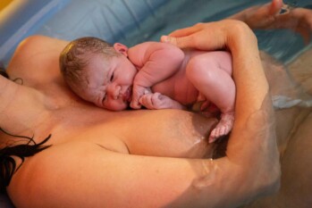 newborn baby on his mother's chest minutes after being born with the umbilical cord till attached