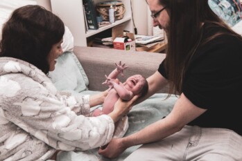 new parents holding their crying newborn baby moments after birth